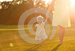 Mum little girl go grass hand sunset beams glares