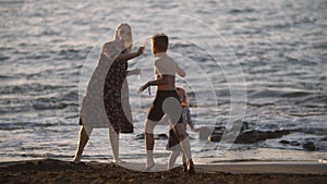 Mum with playful children on the black sand beach. Family vacation