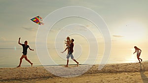 Mum plays with children kite. Children have fun and carefree running on the beach.