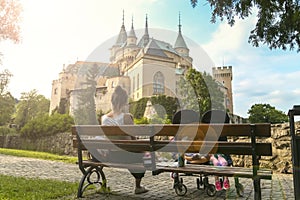 Mum siting on bench on background of beautiful castle