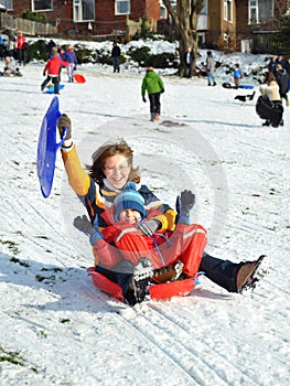 Mum and son in sledge sliding snowy hill, winter