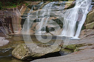 Mumlava waterfall, in the foreground granite stone. Mountain river Mumlava, Krkonose national park, Czech Republic, summer