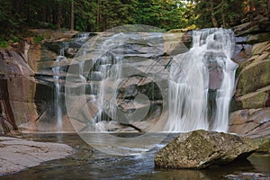 Mumlava waterfall, in the foreground granite stone. Mountain river Mumlava, Krkonose national park, Czech Republic, summer