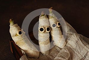 Mummies made of banana and white bandage with eyes on a wooden box