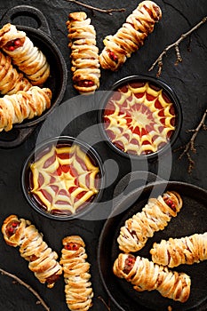 Mummy dogs and ketchup-mustard sauces on a black background  top view.