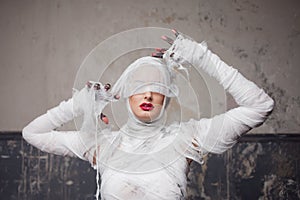 Mummy girl blindfolded. Portrait of a young beautiful woman in bandages all over her body.