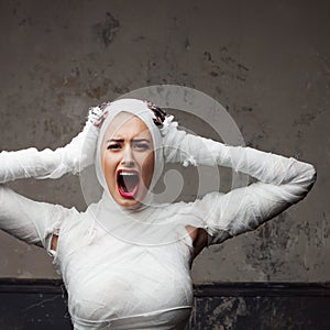 Mummy girl scream in shock. Portrait of a young beautiful woman in bandages all over her body.