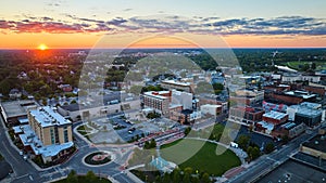Muncie, IN sunset with golden sun over horizon aerial of downtown buildings and Canan Commons Park photo