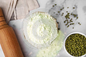 Mung bean flour in paper bag and seeds on white marble table, flat lay