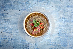 Mung Dhal decorated with red pepper slices at blue tabletop. Moong Dal - Indian Cuisine curry