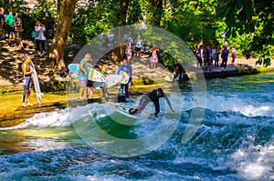 MUNICH, GERMANY, AUGUST 20, 2015: group of surfers is practicing their skill on an artificial wave situated on a small