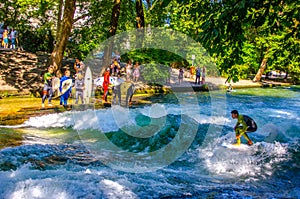 MUNICH, GERMANY, AUGUST 20, 2015: group of surfers is practicing their skill on an artificial wave situated on a small