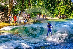 MUNICH, GERMANY, AUGUST 20, 2015: group of surfers is practicing their skill on an artificial wave situated on a small