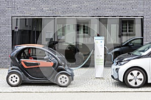 Munich, Germany- June 25, 2016: Two electric cars, Renault and BMW, being recharged at plug-in station in front of modern building