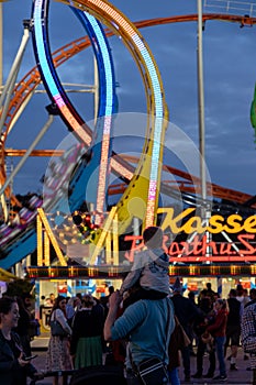 Munich, Germany - September 24: a father is carrying his young son on his shoulders in front of a 5 loop roller coaster on the