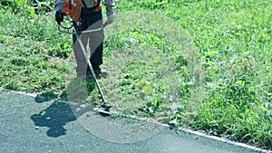 municipal lawnmover man worker cutting grass with disc trimmer at day time in slow motion