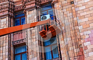 Municipal service workers in orange uniforms on a mobile aerial platform repair festive New Year's electric garlands