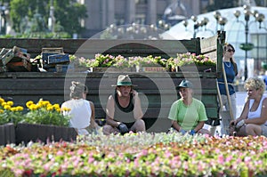 Municipal women workers sitting in the shadow thrown from a truck taking break from caring of a flowerbed