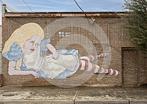 Mural featuring a frustrated Alice in Wonderland by artist Chaitra Linehan in Oak Cliff, Dallas, Texas.