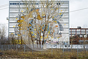 Mural by Ola Volo to pay tribute to the MILE END district of Montreal behind trees photo
