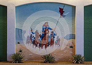 Mural with soldiers on horseback waving guns and riding through a desert on an outside wall of a shooting range in Dallas, Texas.