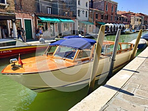 A closeup view of a Venice water taxi docked along a canal in Murano, Italy.