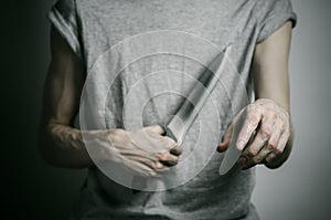 Murder and Halloween theme: a man holding a knife on a gray background