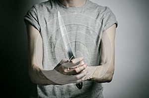 Murder and Halloween theme: a man holding a knife on a gray background