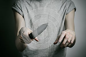 Murder and Halloween theme: a man holding a knife on a gray background