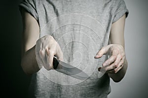 Murder and Halloween theme: a man holding a knife on a gray background