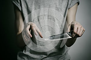 Murder and Halloween theme: a man holding a knife on a gray background