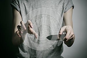 Murder and Halloween theme: a man holding a knife on a gray background