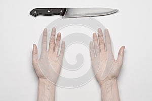 Murder and Halloween theme: A man's hand reaching for a knife, a human hand holding a knife isolated on a gray background in