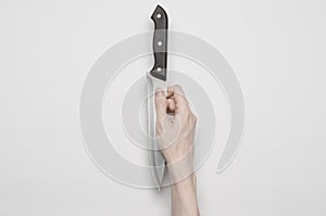 Murder and Halloween theme: A man's hand reaching for a knife, a human hand holding a knife isolated on a gray background in