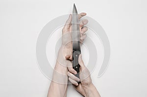 Murder and Halloween theme: A man's hand reaching for a knife, a human hand holding a knife isolated on a gray background in