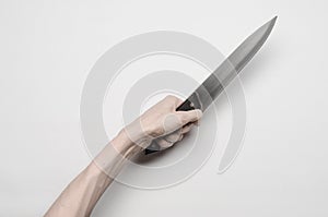 Murder and Halloween theme: A man's hand reaching for a knife, a human hand holding a knife isolated on a gray background in