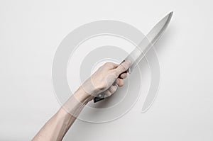 Murder and Halloween theme: A man's hand reaching for a knife, a human hand holding a knife isolated on a gray background in