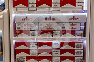 Cigarettes department at a duty free segment store with many big packs of Marlboro on sale on a shelf in shop airport