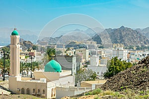 Muscat Takia historical city center streets overview panorama with green mosque dome and rocks in the background, Oman