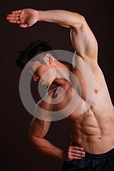 Muscle man stretching left arm and abs