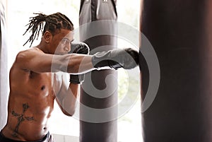 Muscle, punching bag and black man in gym for exercise, boxing challenge or competition training. Power, fitness and