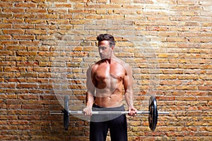 Muscle shaped body man with weights on brick wall