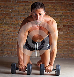 Muscle shaped man on knees with training weights