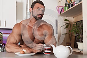 Muscle shirtless bachelor man have a breakfast in kitchen