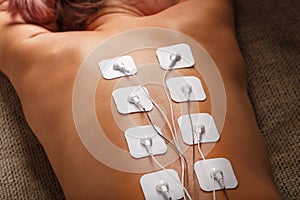 Muscle stimulator with electrodes, bacBack and shoulder massage with a muscle stimulator with attached electrodes along the spine