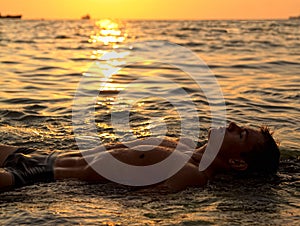 Muscle wet naked man lying in sea water