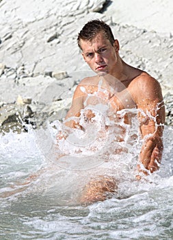 Muscle wet naked man sits in water