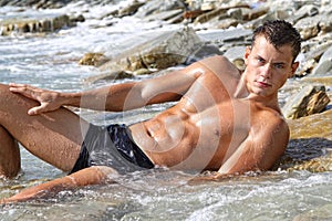 Muscle wet naked man lying in sea water