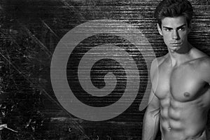 Muscled handsome italian boy on dark vintage background. On side free space. Black and white