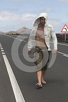 Muscled man walking on the road